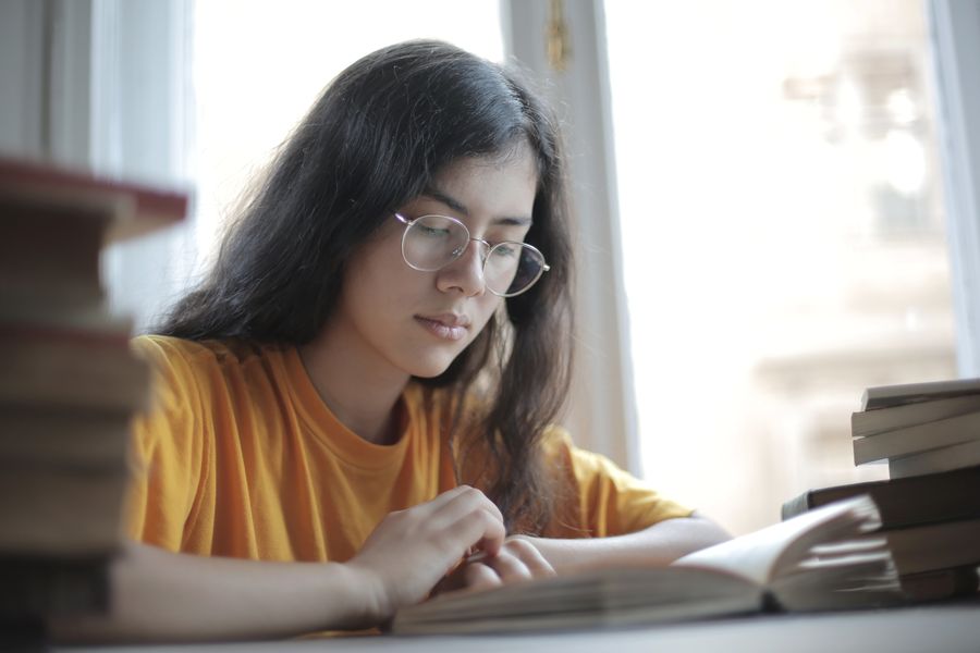 Studentin lernt zwischen Bücherstapeln