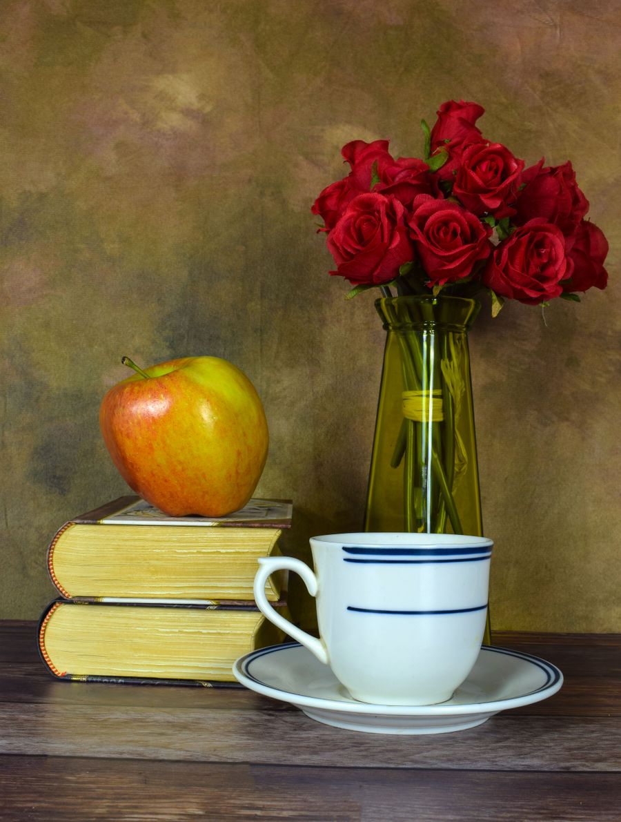 Bücher, ein Apfel und eine Vase auf einem Tisch